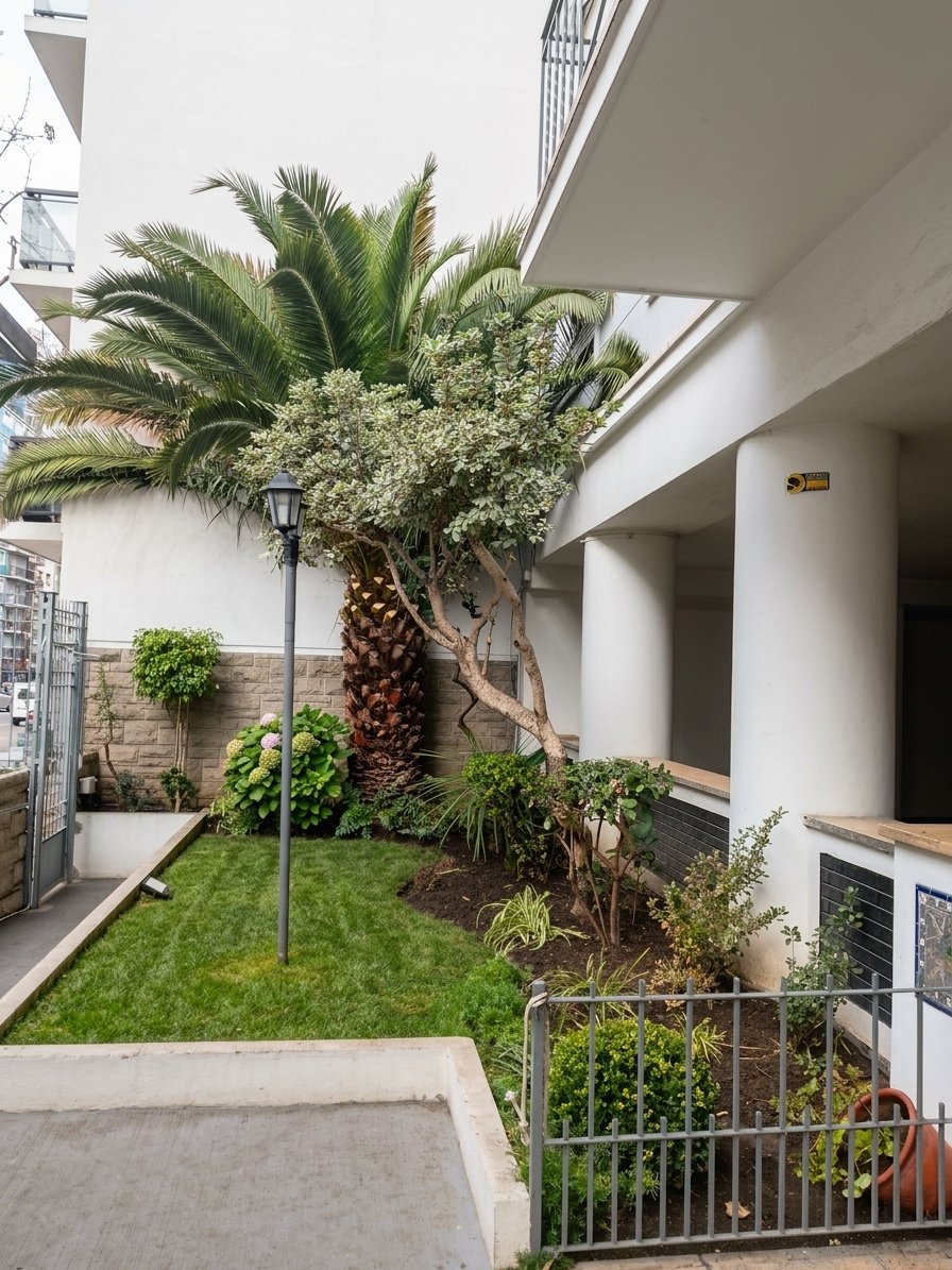 Jardín interno de un edificio con palmera y cantero de flores